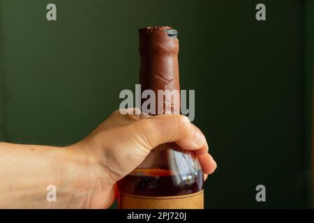 female hand holds a bottle of whiskey in quarantine Stock Photo