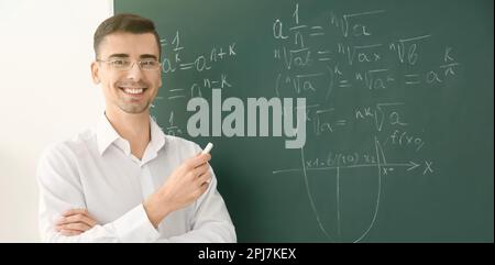 Happy teacher near chalkboard in classroom. Banner design Stock Photo