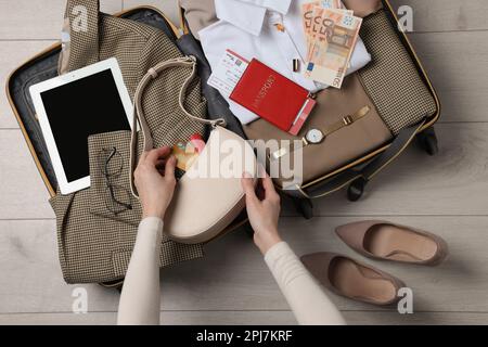 Woman packing suitcase for business trip on wooden floor, top view Stock Photo