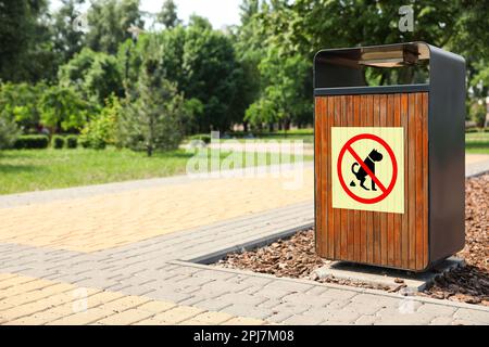 Sign NO DOG WASTE PLEASE CLEAN IT UP on trash bin in park Stock Photo