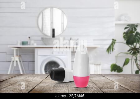 Different roll-on deodorants on wooden table in bathroom. Mockup for design Stock Photo