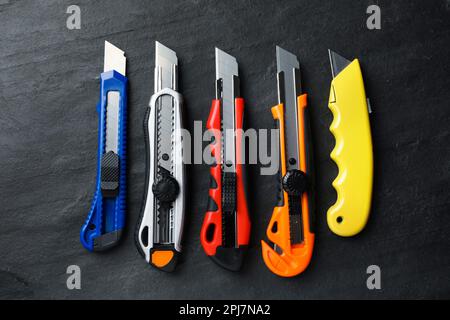 Different utility knives on black table, flat lay Stock Photo