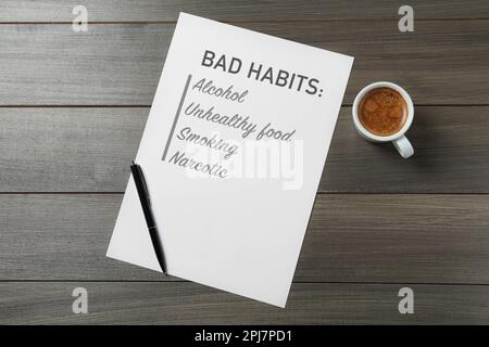 Notebook with list of bad habits, pen and cup of coffee on wooden table, flat lay. Change your lifestyle Stock Photo