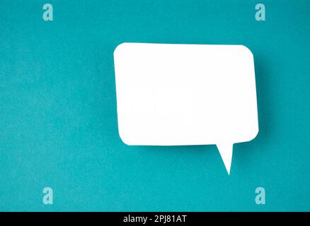 White speech bubble shaped post it note on green background with copy space. Stock Photo