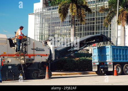 Construction workers use heavy equipment to repair and repave the city street with asphalt in Miami Stock Photo