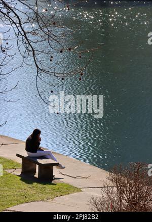 Young woman sitting by Wade Lagoon at University Circle in Cleveland, Ohio Stock Photo