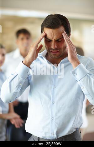 Too much pressure. a businessman suffering from a headache at the office. Stock Photo