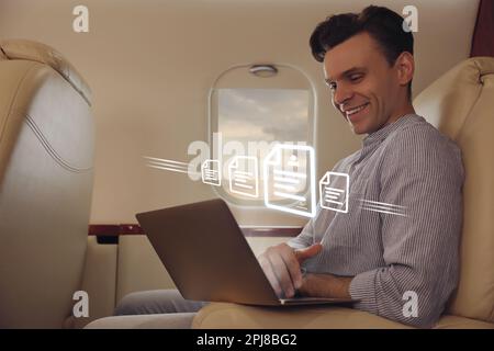 Concept of electronic signature. Man using laptop in airplane during flight Stock Photo