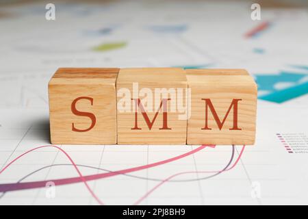 Abbreviation SMM made with wooden cubes on graphical chart, closeup view. Social Media Marketing Stock Photo