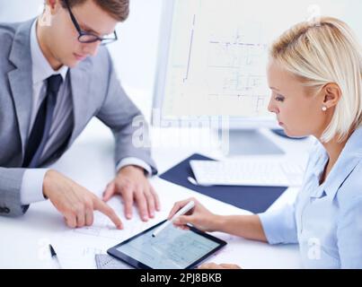 Using the latest technology for accuracy and efficiency. a male and female architect working on a digtial tablet. Stock Photo