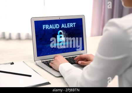 Fraud prevention security system. Woman using laptop at white table, closeup Stock Photo