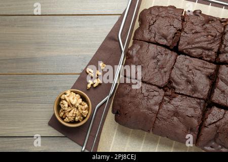 Delicious freshly baked brownies and walnuts on wooden table, flat lay. Space for text Stock Photo