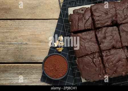 Delicious freshly baked brownies, cocoa powder and walnuts on wooden table, flat lay. Space for text Stock Photo