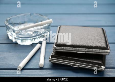 Closed leather cigarette cases with ashtray on blue wooden table, closeup Stock Photo