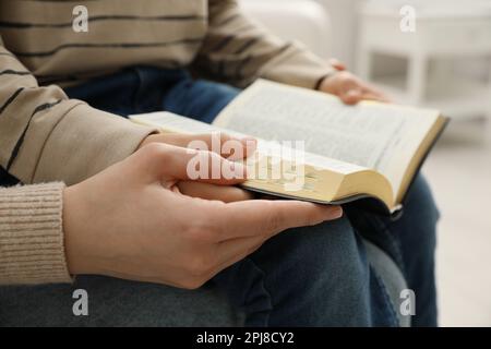 Boy and his godparent reading Bible together indoors, closeup Stock Photo