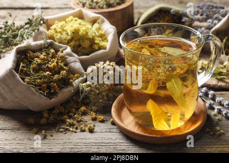 Freshly brewed tea and dried herbs on wooden table Stock Photo