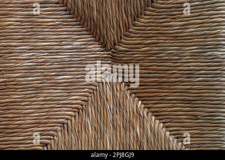 Geometric texture of brown and yellow colored straw chair, usable as a rustic abstract background. Stock Photo