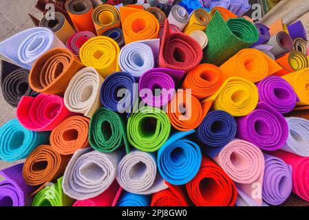 On the street, rolls of felt of different bright colors outside a shop. On the street, rolls of felt of different bright colors outside a shop. Stock Photo