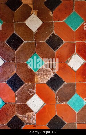 Very old Andalusian Arabic style ceramic tile pattern with geometric shapes and red, orange, green and white colors. Stock Photo