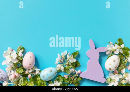 Easter composition with colorful eggs, wooden bunny and spring flowers on a blue background. Spring concept, flowers composition. Greeting card. View Stock Photo