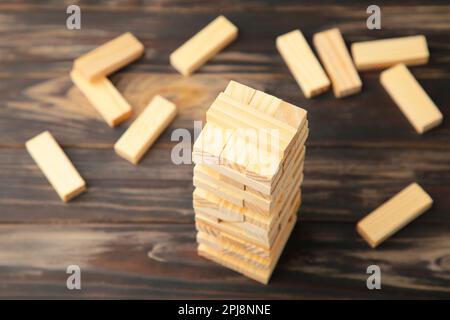 Business risk concept with wood jenga game. Wooden blocks on brown background Stock Photo