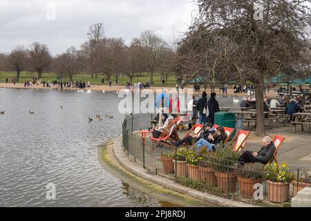 Hyde Park London, people sitting by the late at the Serpentine Bar and Kitchen, outdoor cafe in the springtime Stock Photo