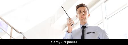 Male security guard with portable radio transmitter indoors. Banner design Stock Photo