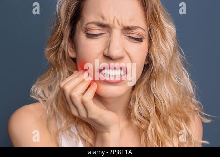 Young woman suffering from toothache on dark blue background Stock Photo