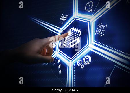 Man pointing at virtual screen with icon of computer file on dark background, closeup Stock Photo