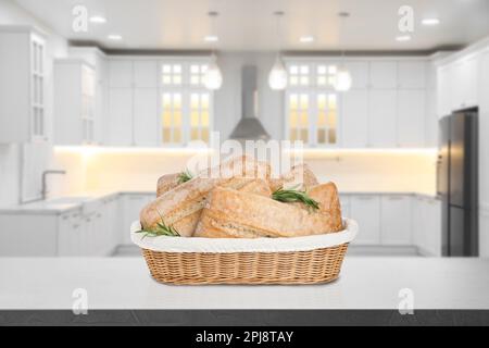 Fresh bread in wicker basket on grey table in kitchen Stock Photo