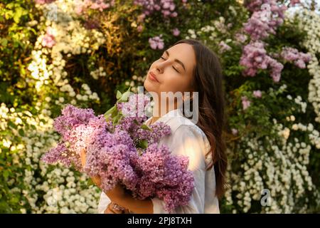 Attractive young woman with lilac flowers outdoors Stock Photo