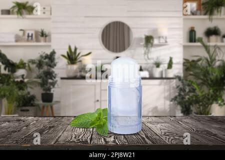 Roll-on deodorant and mint on wooden table in bathroom. Mockup for design Stock Photo