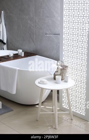 Modern white tub and table with toiletries in bathroom. Interior design ...