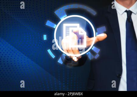 Man pointing at virtual icon of computer file on dark blue background, closeup Stock Photo