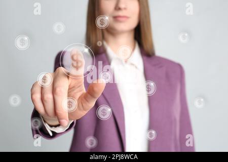 Woman pointing at virtual dollar sign on light background, closeup Stock Photo