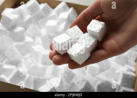 Woman holding styrofoam cubes over box, closeup Stock Photo