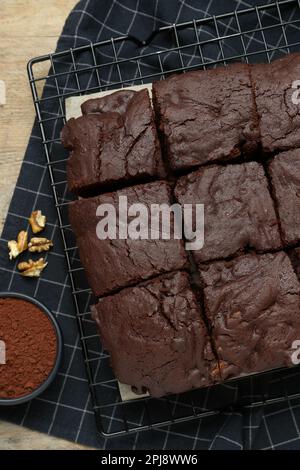 Delicious freshly baked brownies, cocoa powder and walnuts on wooden table, flat lay Stock Photo