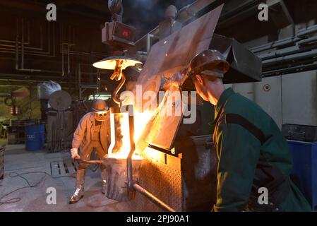 workers in a foundry casting a metal workpiece - safety at work and teamwork Stock Photo