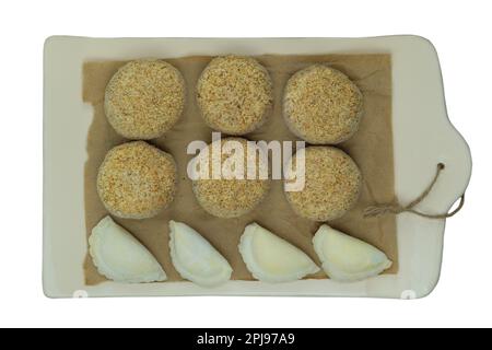 Assorted homemade semi-finished products on wooden board. Frozen cutlets and dumplings. Preparations of homemade food. Stock Photo