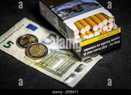 HAARLEM - A pack of cigarettes together with two two euro coins and a note of 5. The excise duty on tobacco will increase by 1.22 euros on Saturday 1 April. For a pack of twenty cigarettes, an average of 9 euros must be paid. In a year's time, another 1.22 euros will be added and a pack of cigarettes will cost an average of 10 euros. ANP REMKO DE WAAL netherlands out - belgium out Credit: ANP/Alamy Live News Stock Photo