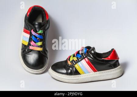 Cute black children gym shoes with cheerful rainbow laces Stock Photo