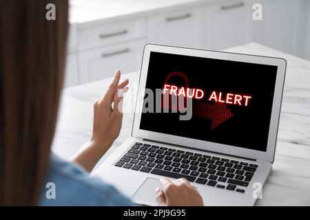 Fraud prevention security system. Woman using laptop at white table, closeup Stock Photo