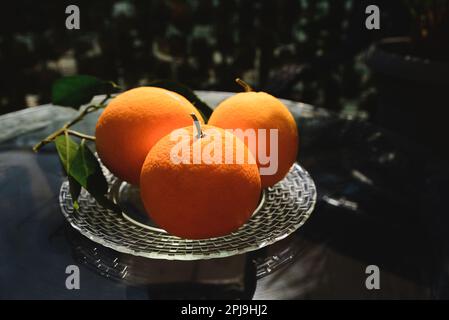 Plate with fresh ripe oranges on glass table outdoors Stock Photo