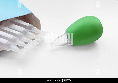 Package with single dose ampoules of sterile isotonic sea water solution and nasal aspirator on white background, closeup Stock Photo