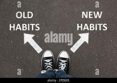 Person standing near arrows with two opposite directions to Old and New Habits on asphalt, top view Stock Photo