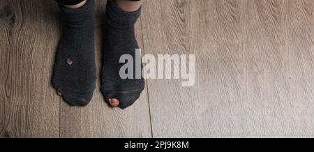 Poority concept image. Woman in socks with holes Stock Photo - Alamy