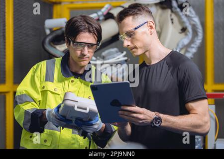 engineer team working program robot welding arm in automated factory. robotic specialists talking together in machine industry manufactory Stock Photo