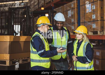 engineer staff worker working together. black african with caucasian male and woman worker team in warehouse Stock Photo