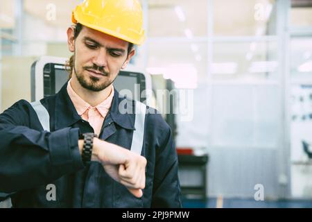 engineer worker looking at wristwatch. industry factory working hours afternoon break times for lunch Stock Photo