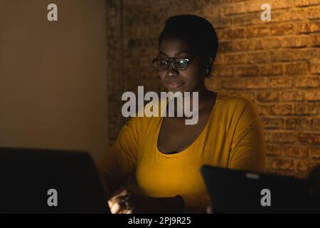 african black business woman night working on laptop computer hard work overnight Stock Photo